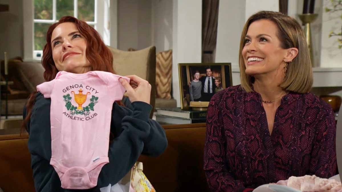 Sally, sitting beside Chelsea and holding up a pink onesie on Young And The Restless